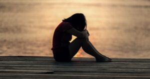 femme au bord de mer, couché de soleil, semble seule et fatiguée